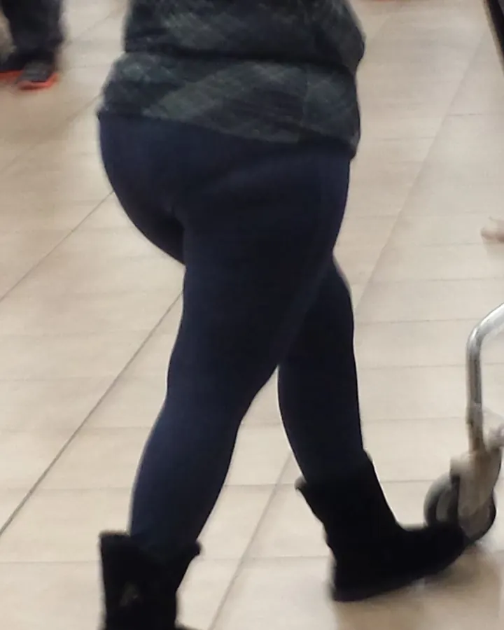 Femme aux cheveux châtains, portant un haut noir et une jupe noire, debout dans un salon.